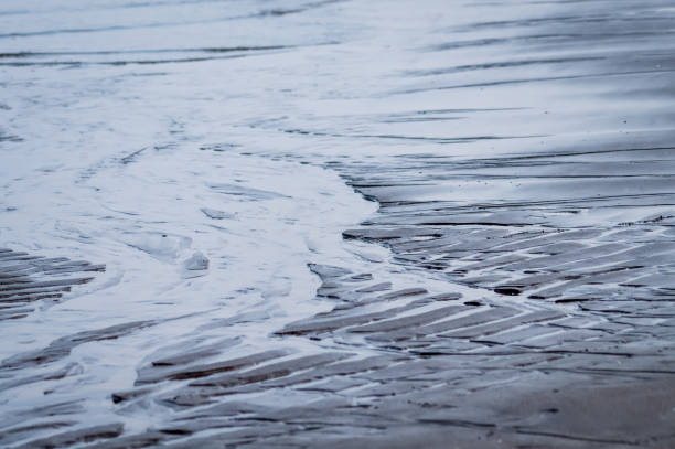 istock wet rippled sand and water at the beach abstract 650363928
