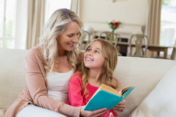 istock Mother and daughter reading a novel on the couch 650403266
