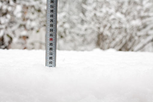 ruler tape measure in white snow cover closeup on winter outdoor background