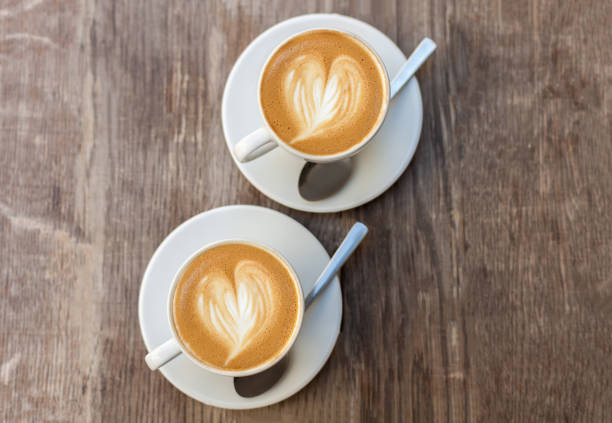 istock A two cup of coffee with heart pattern in a white cup on wooden background 650426396
