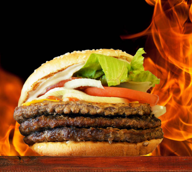 istock Hamburger on wooden plate against flame background 650429300