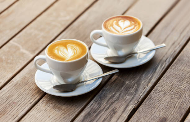 istock A two cup of coffee with heart pattern in a white cup on wooden background 650429308