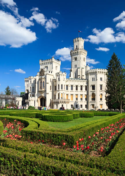Hluboka nad Vltavou, Czech Republic - May 7, 2016: Famous Hluboka nad Vltavou castle in clear spring day with tulips in foreground. Some tourists in background.