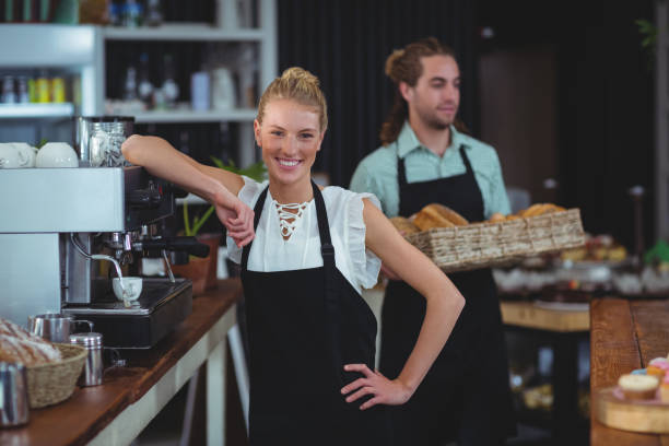 istock Portrait of smiling waitress standing behind counter 650524010