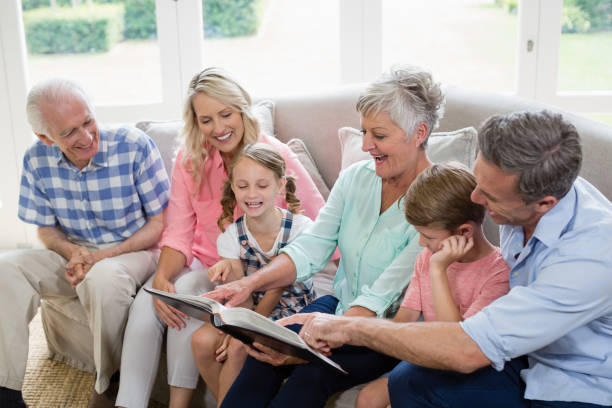 mehr-generationen-familie mit blick auf deren album foto im wohnzimmer - grandmother senior adult child multi generation family stock-fotos und bilder