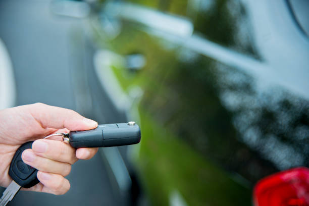 Woman unlocking a car by pressing on the remote control car alarm systems.