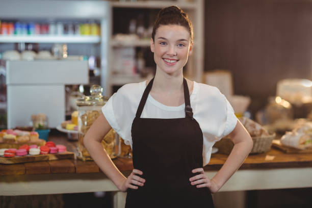 istock Portrait of smiling waitress standing with hands on hip 650607972