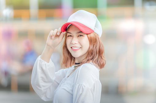 Outdoor portrait of a young beautiful fashionable happy smilng lady posing on  Model wearing hat cap and stylish clothes . Girl looking up. Female fashion. teen lifestyle.bokeh background