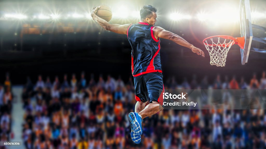 asketball Player scoring an athletic slam dunk shoot Basketball Player scoring an athletic slam dunk shoot Basketball - Sport Stock Photo