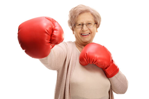 femme âgée joyeuse avec gants de boxe, jetant un coup de poing - boxing glove sports glove isolated old photos et images de collection