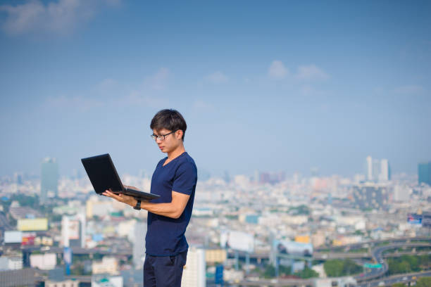 istock Young business man using laptop and digital tablet cityscape background 650624786
