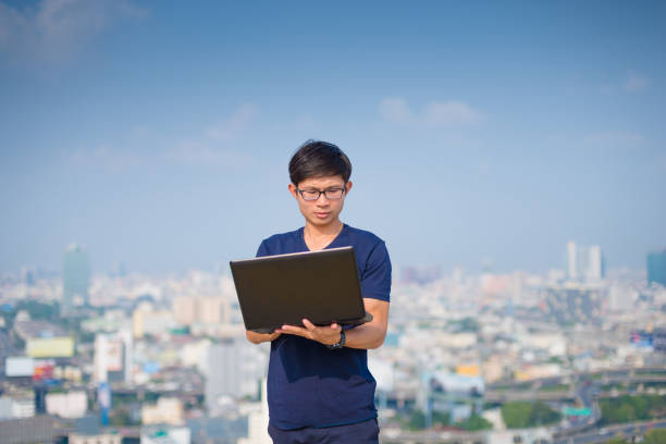 istock Young business man using laptop and digital tablet cityscape background 650624814
