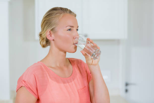 istock Woman drinking water from glass in kitchen 650628160