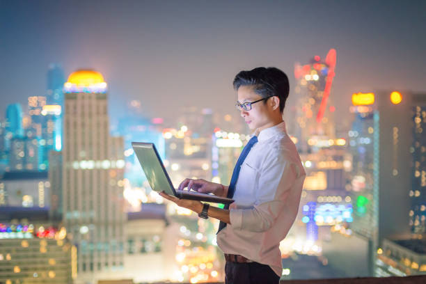 istock Young business man using laptop and digital tablet cityscape background 650628442