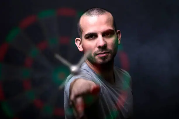 Young man playing a game shooting darts