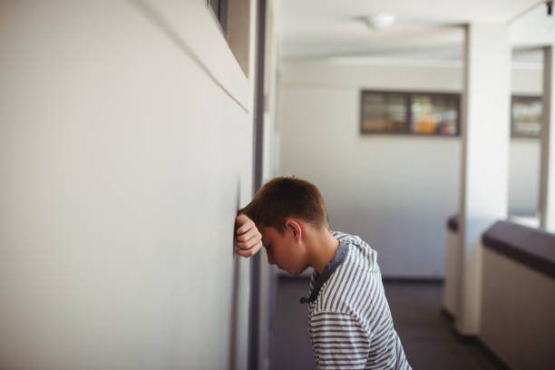 istock Sad schoolboy leaning head against wall in corridor 650629348