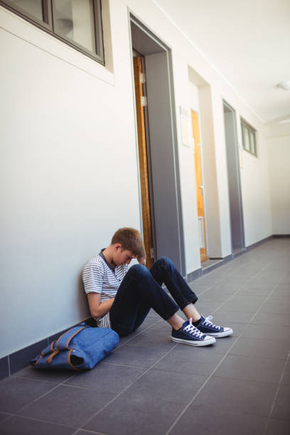 istock Sad schoolboy sitting in corridor 650629660