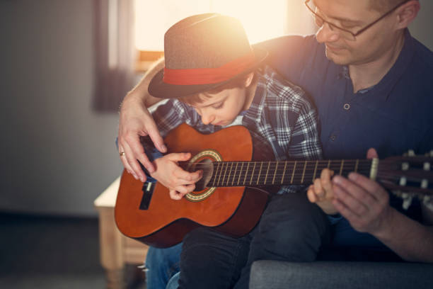 Father teching son to play guitar Father is teaching his 7 year old son to play guitar. 
 father and son guitar stock pictures, royalty-free photos & images