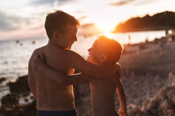 A rearview photo of two brothers in standing at looking at the sun