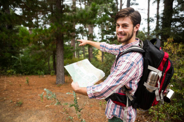 istock Male hiker holding a map and showing direction 650642830