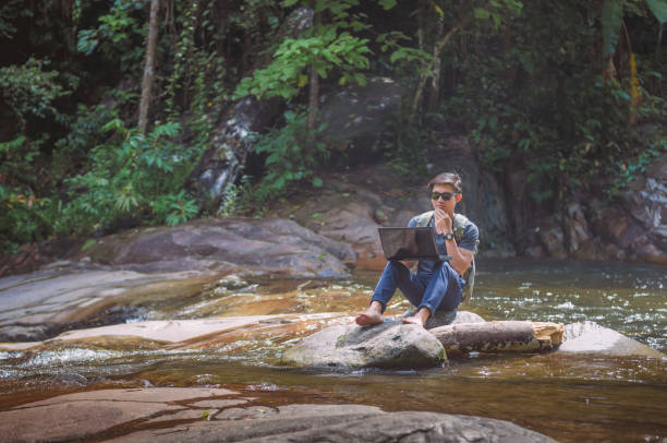 istock Hiker with backpack and laptop and phone at  waterfall  the forest. 650647368