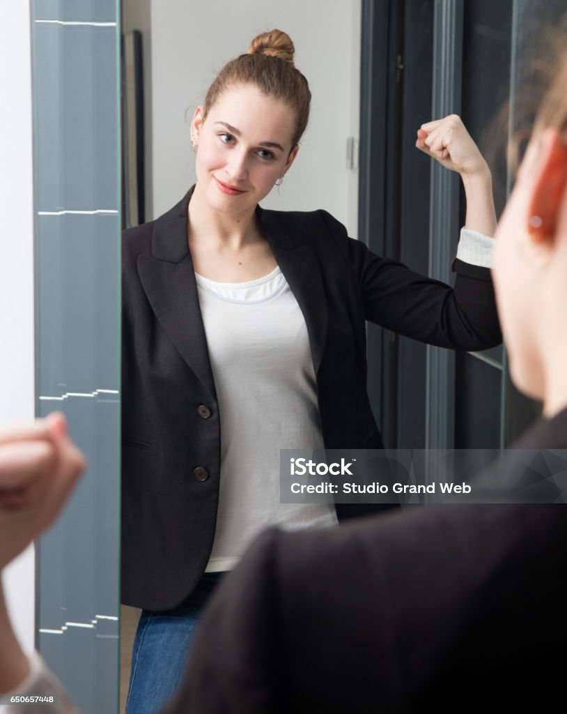 successful beautiful young smart woman with power girl body language motivated beautiful young smart woman preparing herself for business with power girl body language, standing in front of her home mirror for successful morning routine Mirror - Object Stock Photo