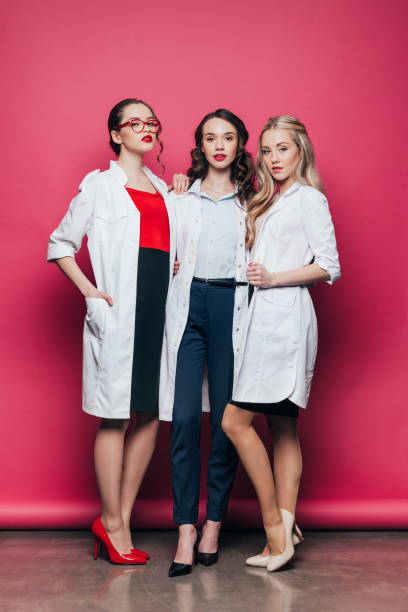 confiante tr�ês médicos em uniformes médicos em rosa - scientist sensuality women lab coat - fotografias e filmes do acervo