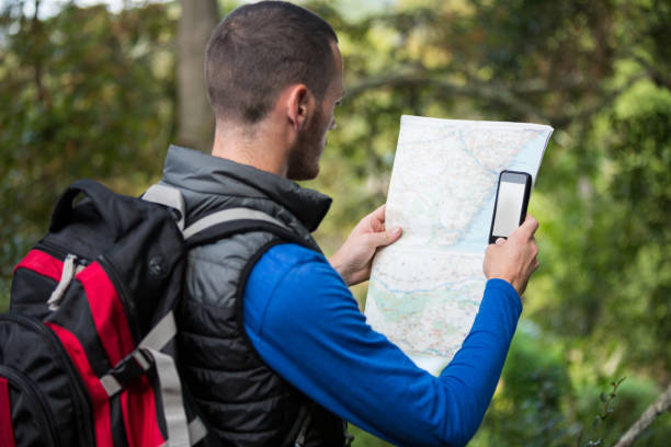 istock Male hiker looking at map and mobile phone 650669464