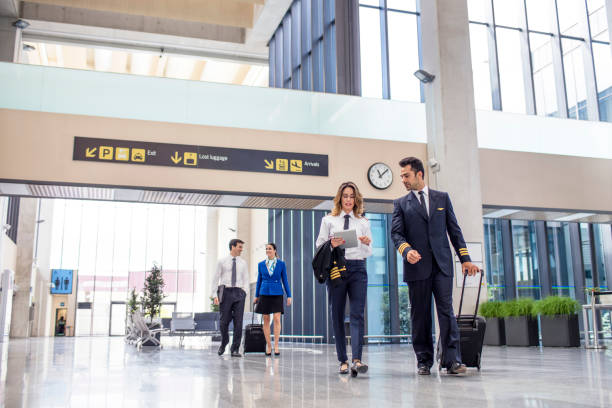 flugpersonal mit gepäck und tablet zu fuß in flughafen - journey elegance people traveling architecture stock-fotos und bilder