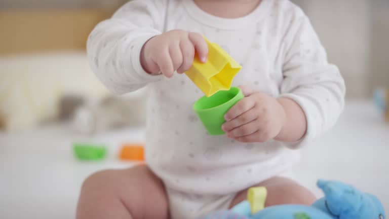 Sitting baby boy playing with plastic shape blocks