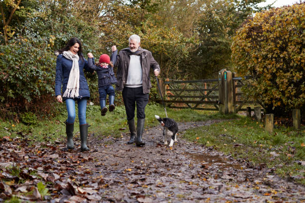famiglia multi-generazione porta il cane a camminare nel paesaggio autunnale - senior adult winter senior women daughter foto e immagini stock
