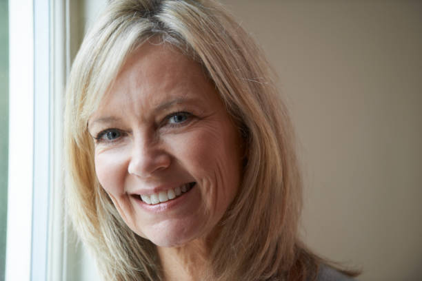istock Smiling Mature Woman Standing Next To Window 650702872
