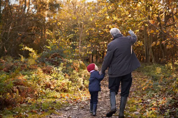 Photo of Grandfather And Granddaughter Enjoying Autumn Walk
