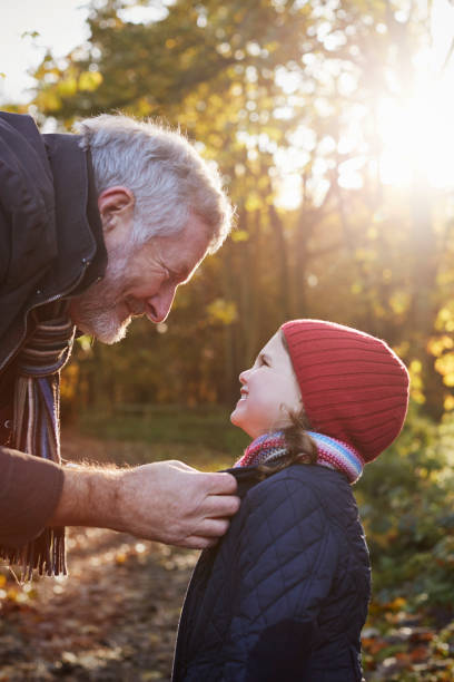 istock Grandfather Tying Granddaughter's Scarf On Autumn Walk 650703032