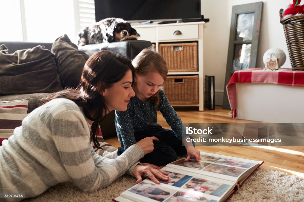 Mère et fille à la maison à la recherche grâce à l’Album Photo - Photo de Regarder libre de droits