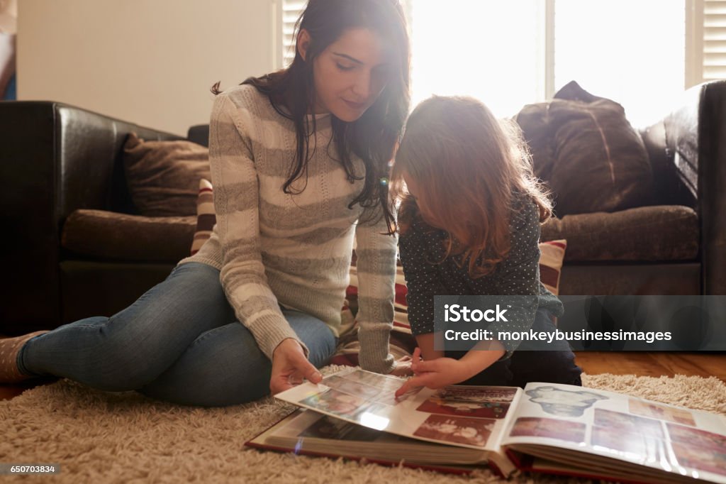 Mother And Daughter At Home Looking Through Photo Album Family Stock Photo