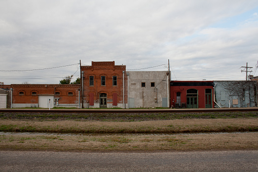 Weathered facades of historic buildings along a railroad track in a rural town in Texas.