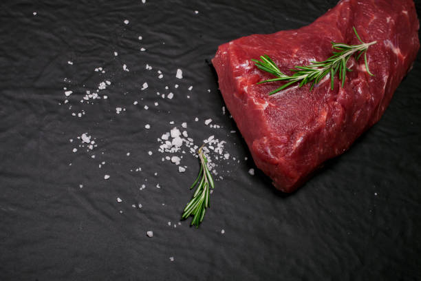 istock Raw beef steak on a cutting board with rosemary and spices. 650707636
