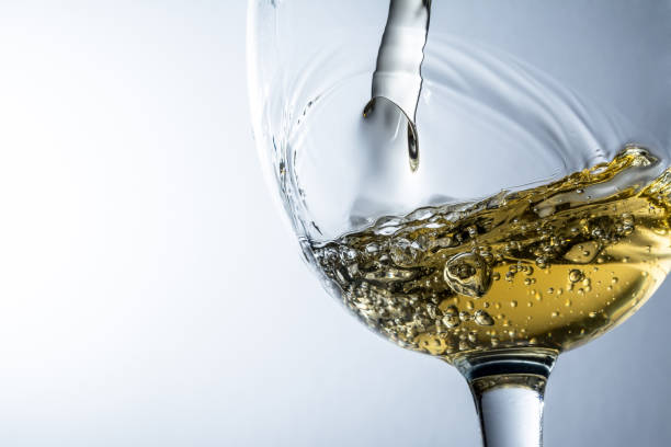 istock White wine splash on grey background, stream of white wine pouring into a glass. 650710804