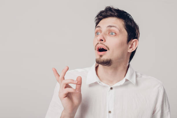 istock young attractive surprised brunette man in white shirt on gray b 650722752