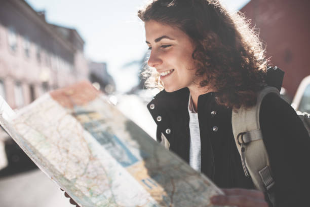 istock Curly woman with backpack and map on the street 650723610