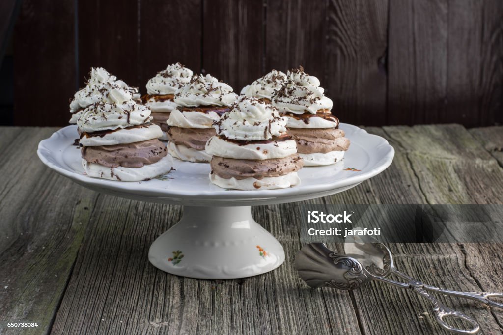 Several Czech sweet dessert "Manicka" - Meringues with chocolate whipped cream and whipped cream on a Plate Several Czech sweet dessert "Manicka" - Meringues with chocolate whipped cream and whipped cream on a Plate on Old Wooden Board Backgrounds Stock Photo