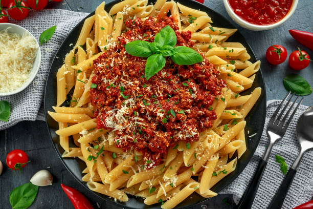 heißen penne pasta bolognese mit parmesan-käse, basilikum, knoblauch, tomaten, chili auf platte. - tomato soup red basil table stock-fotos und bilder
