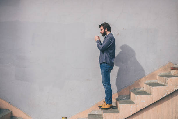 istock Hipster standing on stairs and lighting cigarette 650770828
