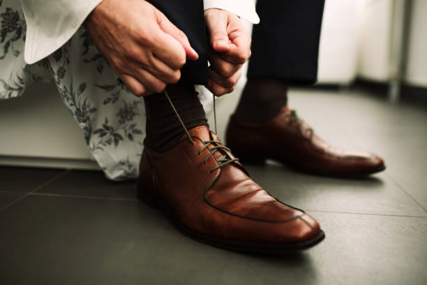 Male tying his shoes Young male sitting on a couch and tying his shoes lace fastener photos stock pictures, royalty-free photos & images
