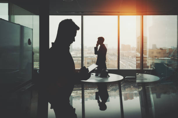 istock Silhouette of two businessmen in office interior 650855774