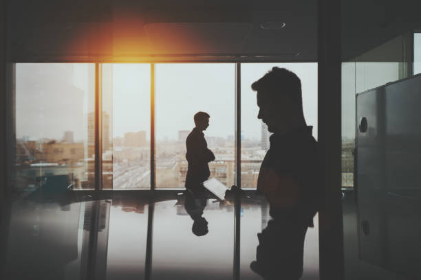 istock Silhouette of two businessmen in office interior 650857916