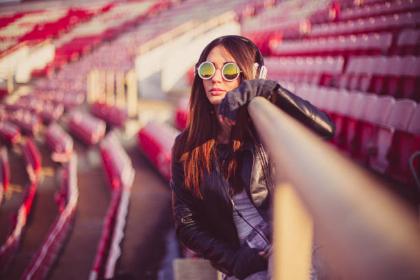 linda garota com um fone de ouvido e o telefone inteligente na tribuna - casual smart casual sex symbol sensuality - fotografias e filmes do acervo