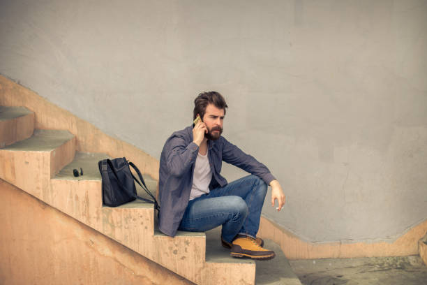 istock Bearded man on the stairs using phone 650961890