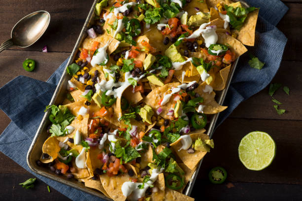 Homemade Loaded Sheet Pan Nachos Homemade Loaded Sheet Pan Nachos with Cilantro Lime Tomato and Onion nacho chip photos stock pictures, royalty-free photos & images